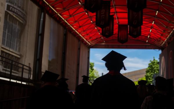 Student in cap and gown walking into OSU Stadium for Graduation